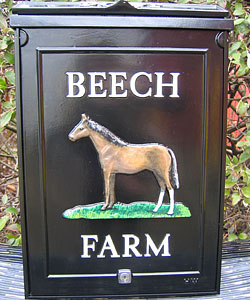 An example of a large personalised post box set out in white Times lettering in straight lines above and below the horse emblem